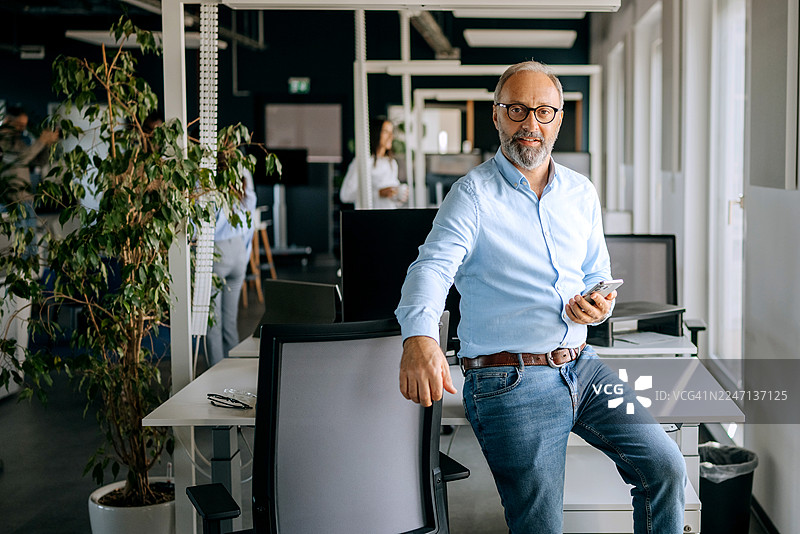 一位衣着考究的成熟商人正在办公室对着镜头摆姿势图片素材