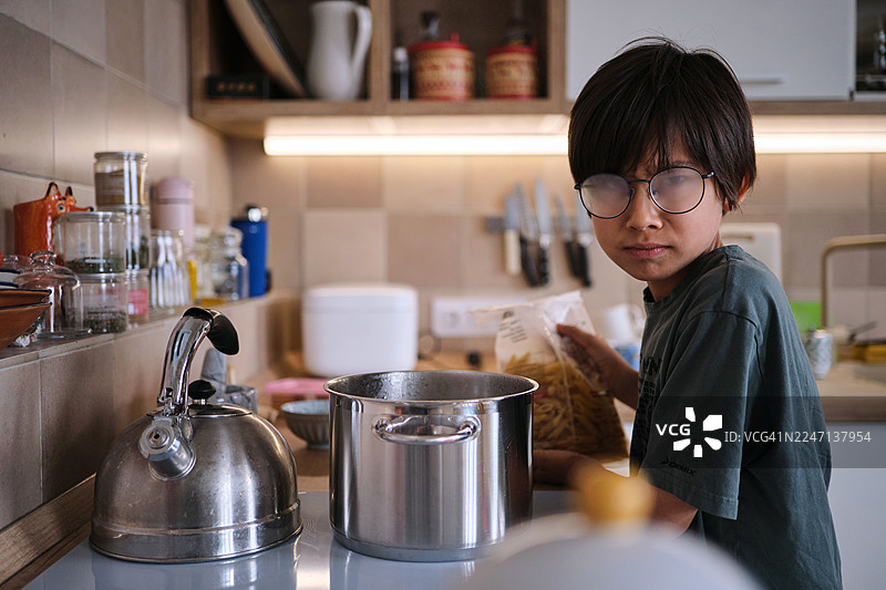 男孩在家里的厨房学习做意大利面图片素材