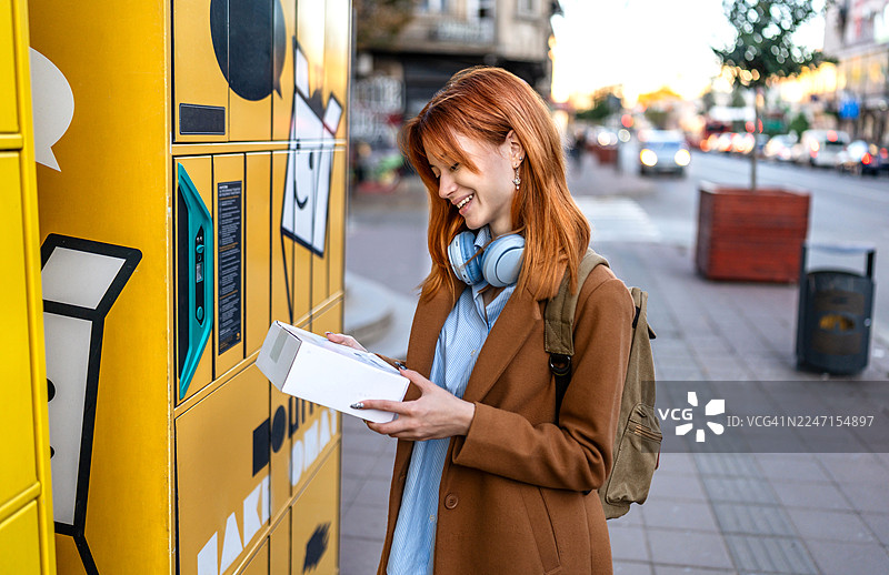 年轻女子在城市中从智能储物柜接收包裹图片素材
