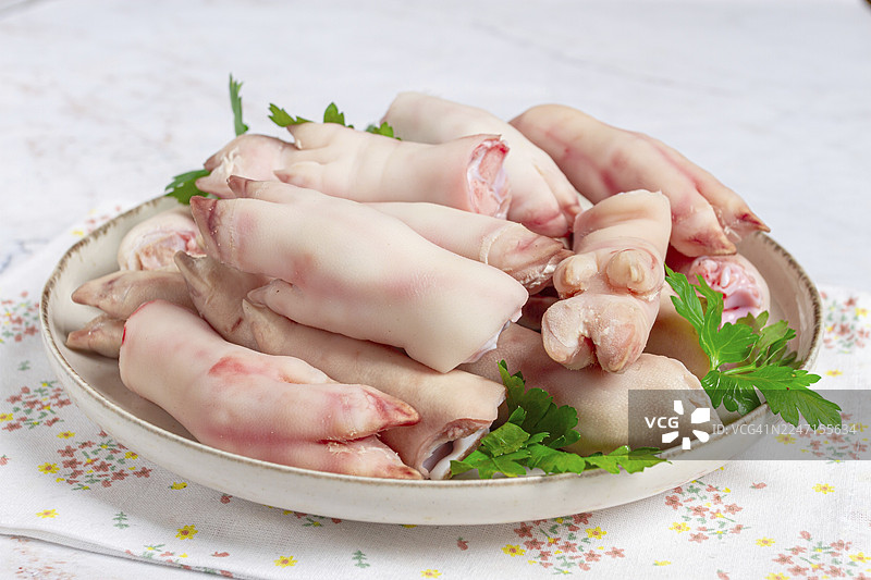 白色背景上摆放着猪蹄，上面装饰着新鲜的欧芹图片素材