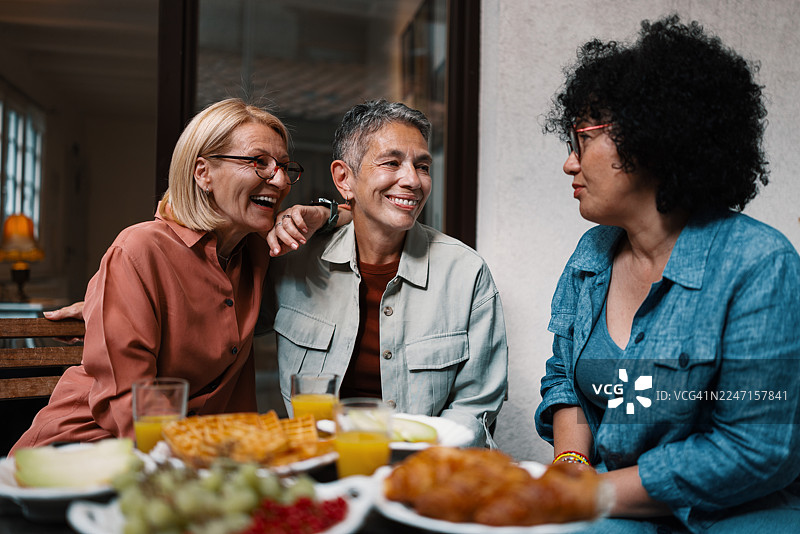 阳光明媚的露台上，快乐的女性正在浏览在线约会和社交图片素材