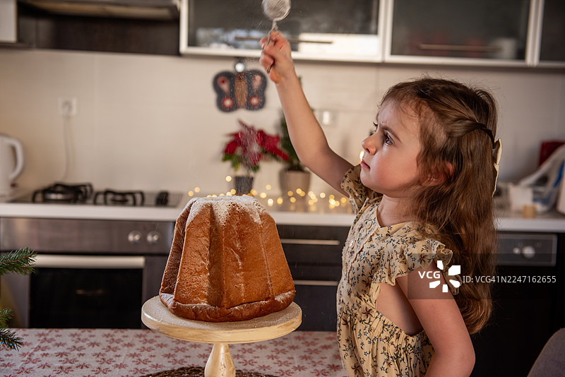 小女孩在用糖粉装饰潘多罗蛋糕图片素材
