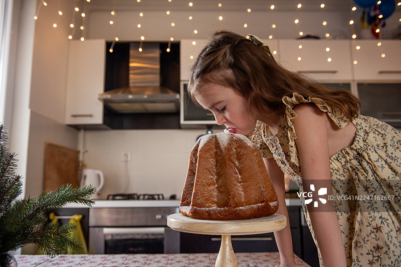 小女孩舔食潘多洛圣诞蛋糕上的糖粉图片素材