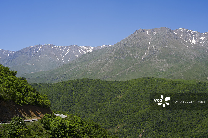蓝天下的绿色林山与雄伟山脉，亚美尼亚锡尼克省塔什通山口附近的M2公路景观图片素材
