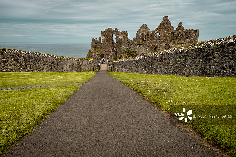 阴云密布的天空下，海边通往古代城堡遗迹的空旷小径，英国，邓路斯城堡图片素材