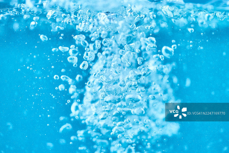 清澈水中上升的蓝色水下气泡图片素材