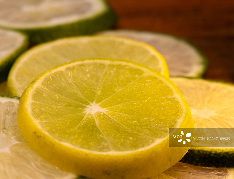木质表面上鲜艳的柠檬和青柠切片特写，展示新鲜的柑橘类水果图片素材