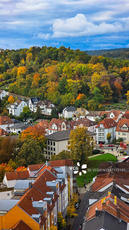 从高处俯瞰城镇，秋季色彩斑斓的树木和房屋在阴云密布的天空下，德国，巴特赫斯费尔德图片素材