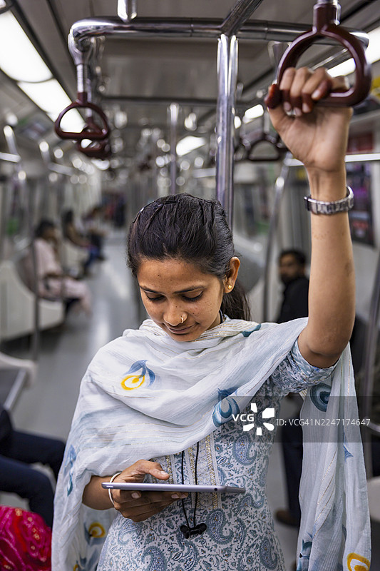 印度斋浦尔，年轻的通勤者在地铁上使用平板电脑图片素材