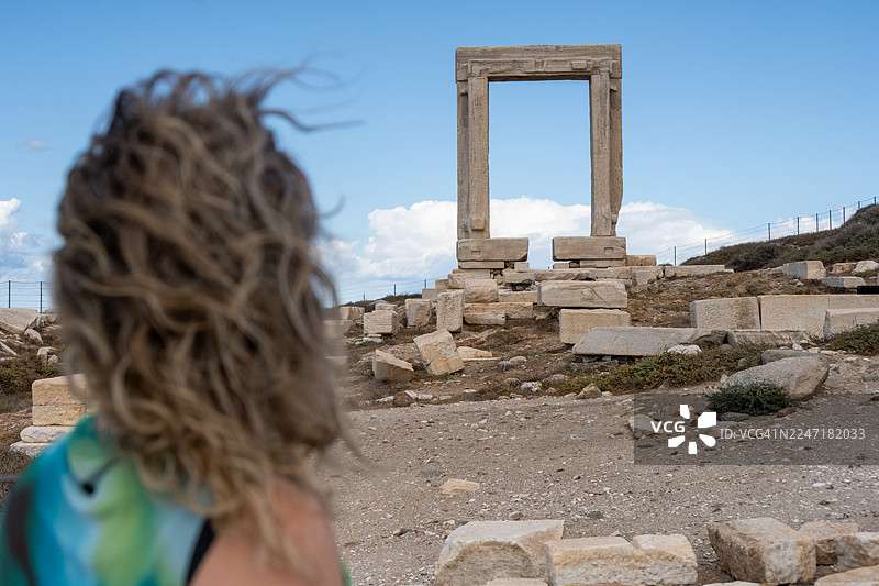 希腊基克拉泽斯群岛纳克索斯岛纳克索斯岛波尔塔拉神庙（阿波罗神庙入口）前的一位年轻女游客图片素材