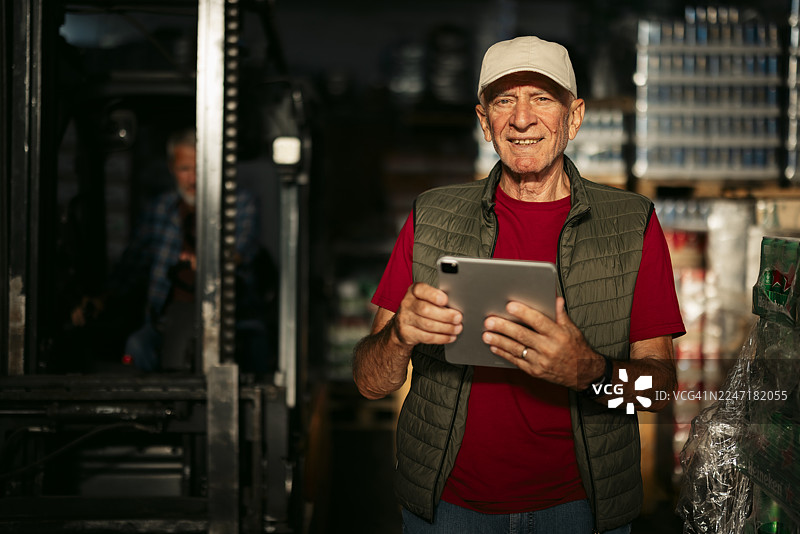 年长的仓库工作人员正在使用平板电脑检查库存图片素材