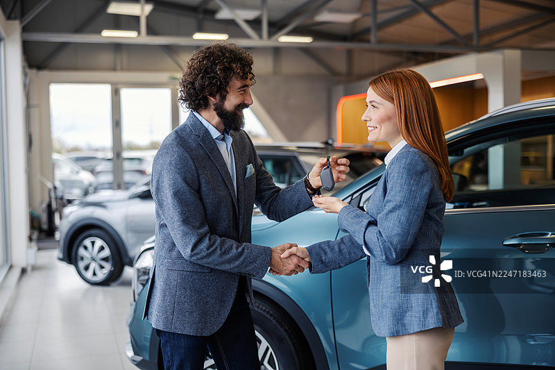 客户接过新车钥匙并与销售人员握手图片素材