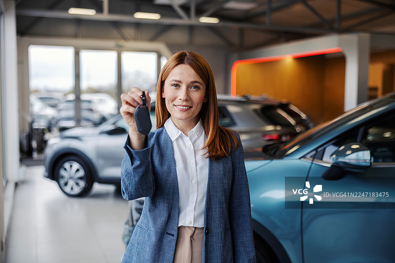 快乐的女士在经销商处拿着新车的钥匙图片素材