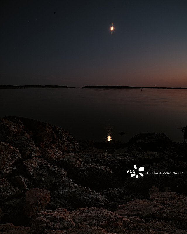 夜幕下，月光洒在宁静的海面和岩石海岸上，美国缅因州巴斯港的巴斯港头灯站风景优美。图片素材