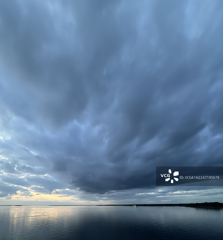傍晚时分，平静的海面映照着戏剧性的暴风云和天空，地点为芬兰奥卢的纳利卡林海滩。图片素材