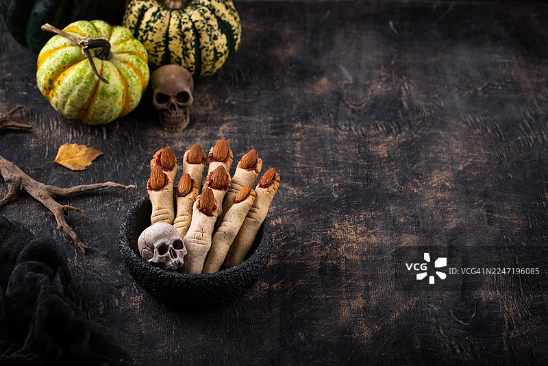 俯视视角拍摄的万圣节女巫手指饼干和南瓜摆放在深色桌子上图片素材