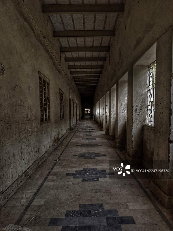 长而黑暗空旷的老建筑走廊，带有窗户和图案地板，位于巴基斯坦拉尔卡纳图片素材