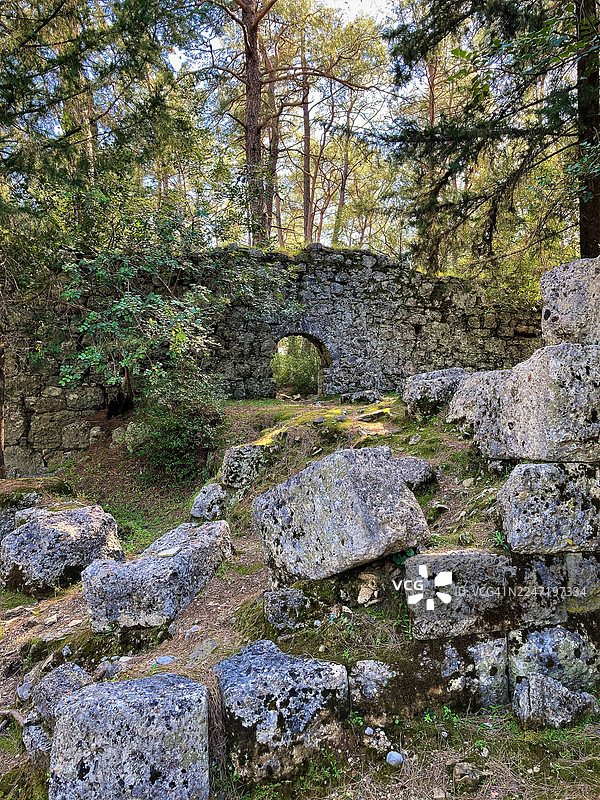 阳光明媚的森林景观中，古老的石头遗迹与拱门静静伫立图片素材