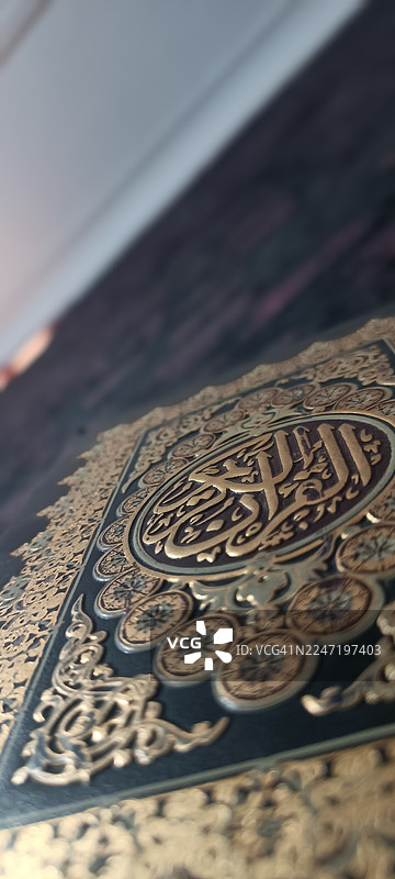 特写镜头：一本华丽的、带有金色压花圣书，上面有阿拉伯书法，象征着信仰和传统图片素材
