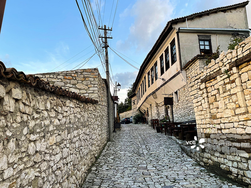 阿尔巴尼亚一座历史古城的空旷鹅卵石小巷，两侧是传统石砌建筑，天空晴朗图片素材