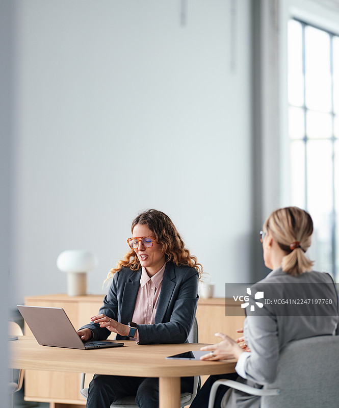 现代办公室里的专业女性，使用笔记本电脑和文件开会图片素材