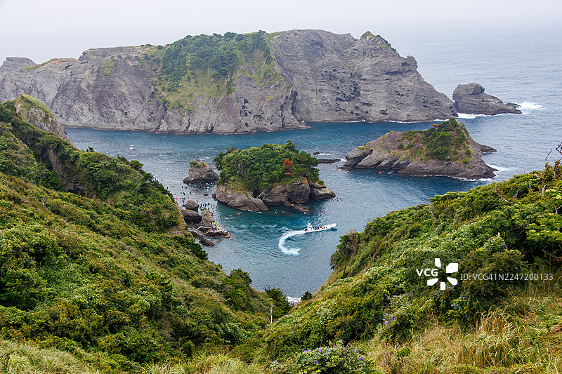 从海角天文台俯瞰的日向海岸美丽蔚蓝大海。可以看到鬼之岛等无人岛、小岛以及当地的岩石海岸。潜水员和浮潜者乘船出海。图片素材