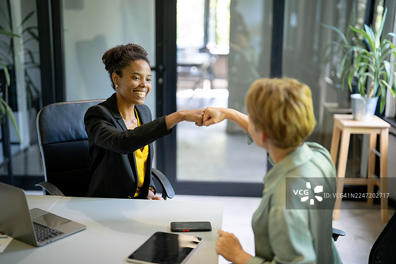 两位女商人成功达成交易后在办公室里击掌庆祝图片素材