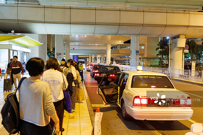 人们在出租车站等车。一辆冲绳风格的菠萝出租车抵达。图片素材