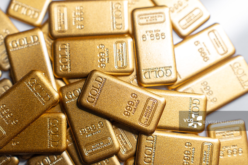 金条堆叠在白色背景上，象征着财务安全和长期资产保护。图片素材