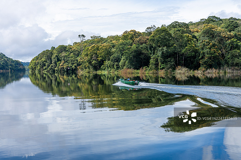 船只划过印度喀拉拉邦泰卡迪佩里亚尔湖国家公园的天空与山峦倒影图片素材