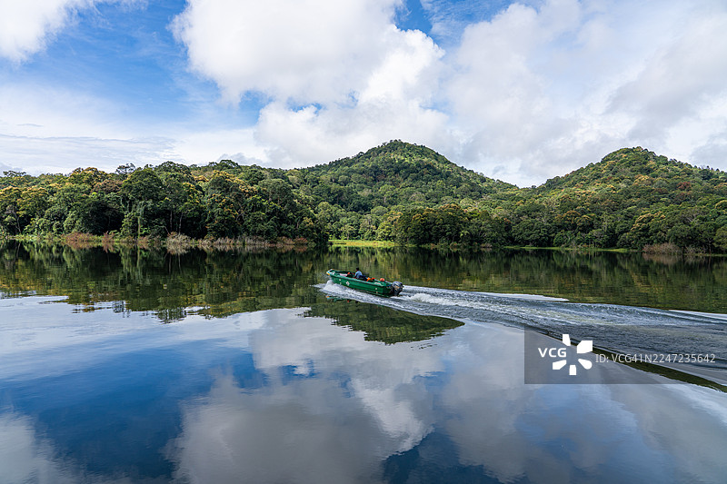 船只划过印度喀拉拉邦泰卡迪佩里亚尔湖和国家公园的天空与山峦倒影图片素材