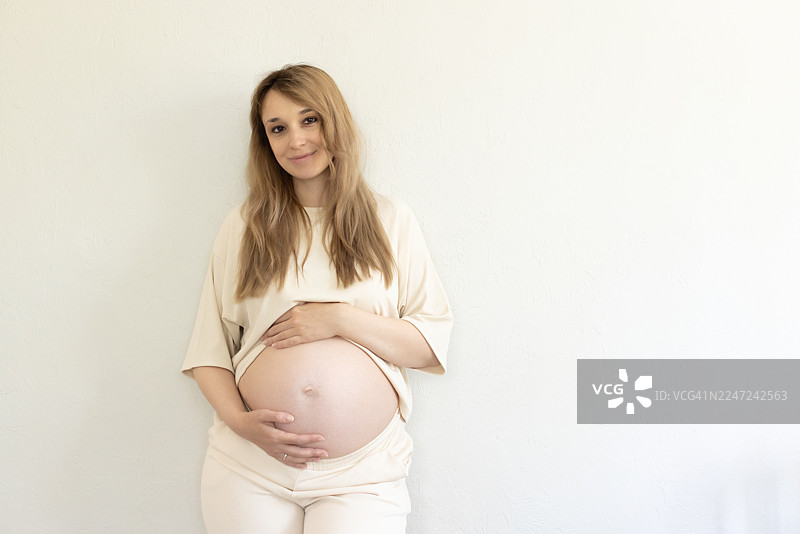 一位美丽的、宁静的孕妇的孕肚，她轻轻地将手放在腹部，象征着母性的喜悦与期待。图片素材