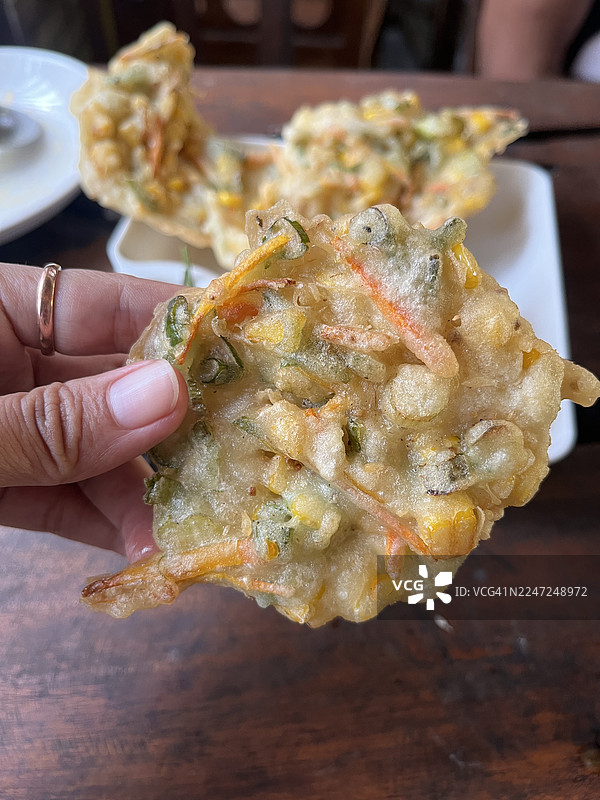 特写一只手拿着印尼玉米饼（Bakwan Jagung）图片素材