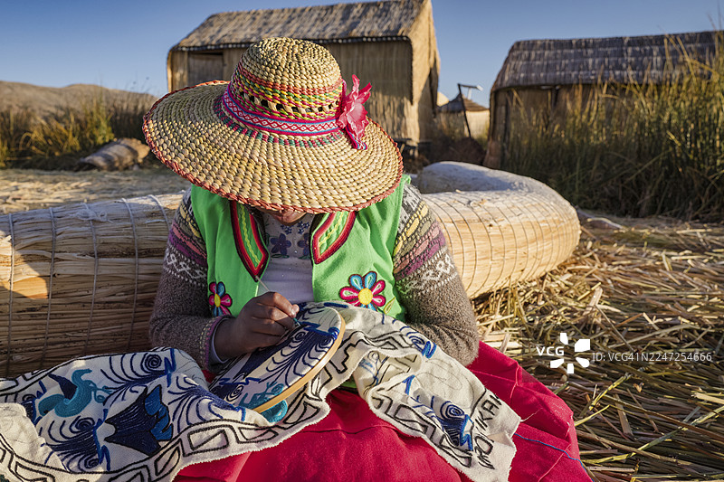 秘鲁乌鲁族浮岛上的年轻女子售卖纪念品，的的喀喀湖，秘鲁图片素材