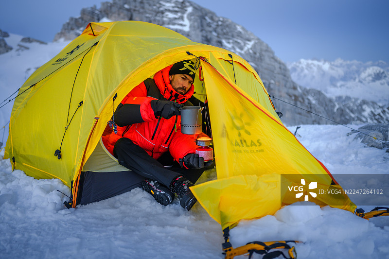 雪山之夜，登山者在灯火通明的帐篷里享用热餐图片素材