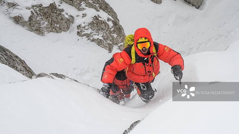 身着鲜艳装备的登山者，带着坚毅的决心，攀登高山雪峰图片素材