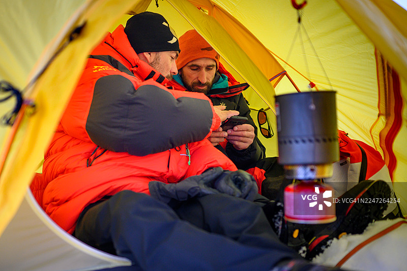 经验丰富的登山者在夜晚的帐篷内使用露营炉享用热餐图片素材