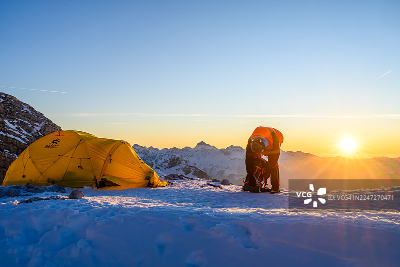 日出时登山者在雪山高营地整理装备图片素材