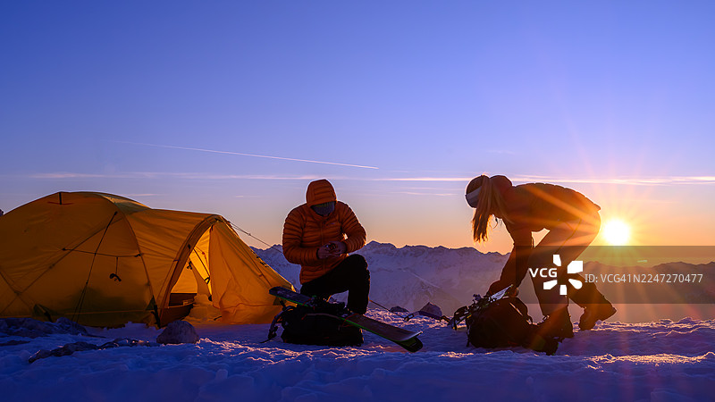 中龄白人夫妇在日出山地营地兴致勃勃地准备滑雪装备图片素材