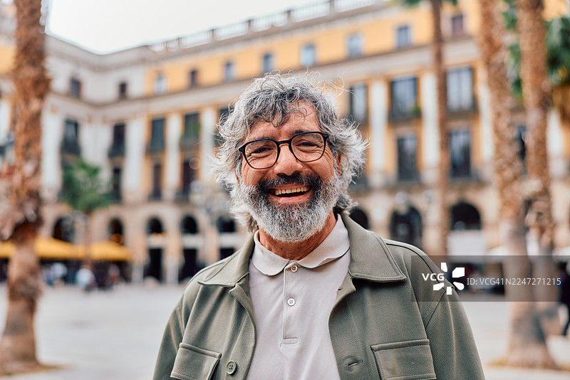 快乐的老年男子在巴塞罗那城市广场上微笑图片素材