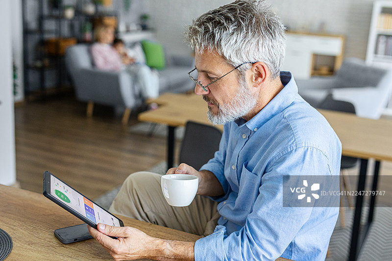 成熟男性在智能家居应用上查看能源使用情况图片素材