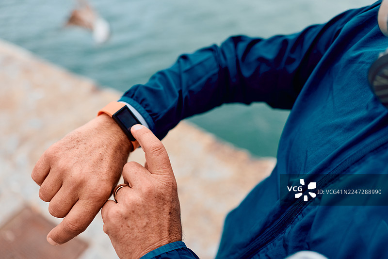 年长男性在户外锻炼时查看健身追踪器图片素材