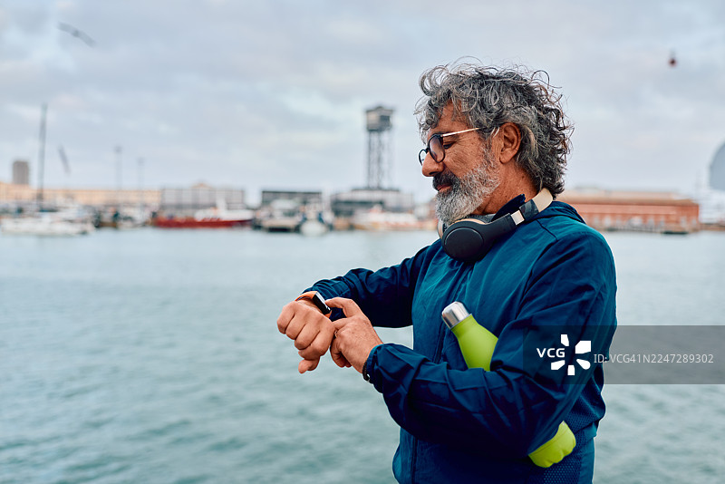 中年男子在户外锻炼时查看智能健身手表图片素材