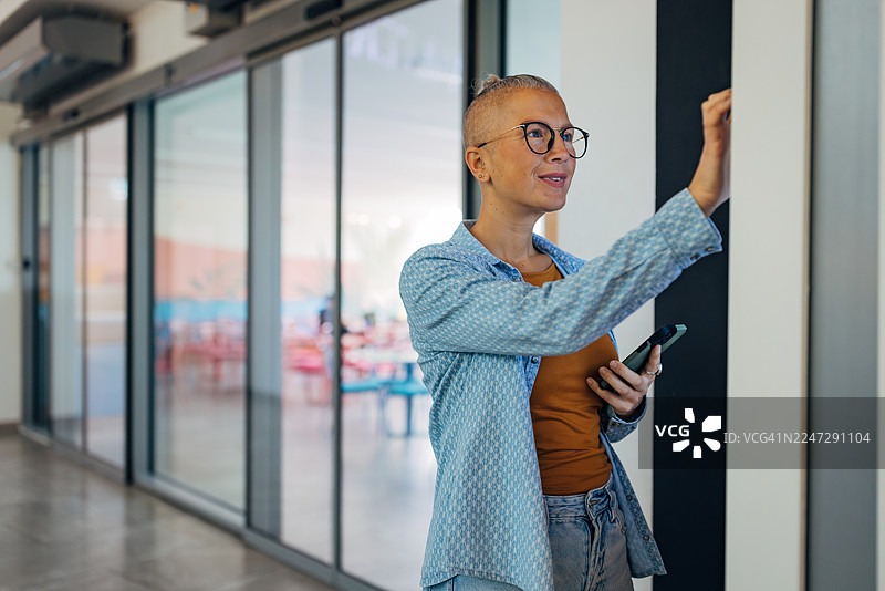 一位无忧无虑的女士在现代快餐店使用数字触摸屏自助点餐机点餐。女顾客正在与自助点餐技术互动。图片素材