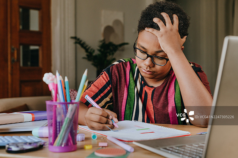 疲惫沮丧的男孩在家坐在桌前用笔记本电脑在线学习图片素材