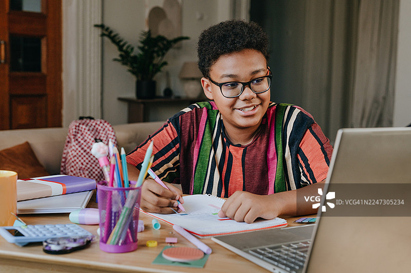 男孩在家坐在桌前用笔记本电脑在线学习图片素材