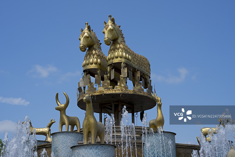 格鲁吉亚伊梅列季大区库塔伊西市大卫·阿格马什内贝利中央广场的科尔喀斯喷泉,在晴朗的天空下,展示着令人印象深刻的带有金马和金羊雕像的喷泉。图片素材