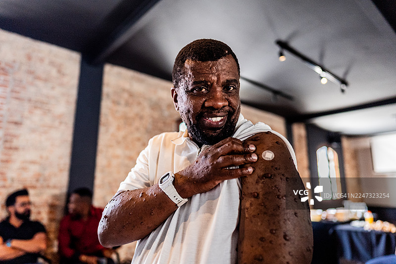 一位成熟男士在疫苗接种中心展示接种疫苗后的创可贴肖像图片素材