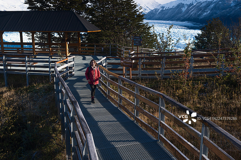一位女士在巴塔哥尼亚佩里托莫雷诺冰川的步道上徒步，欣赏着冰川美景图片素材