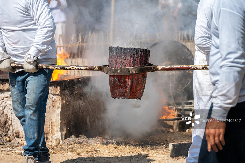 泰国铁匠用铁钳从熔炉中夹起炙热的坩埚，特写镜头图片素材